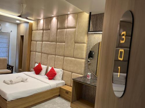 a bedroom with a bed with red pillows and a mirror at Soho House by Jayshrea in Chandrapur