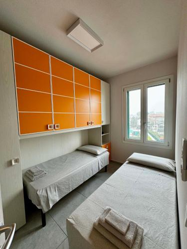 two beds in a room with orange cabinets and a window at Suite Nazioni in Lido delle Nazioni
