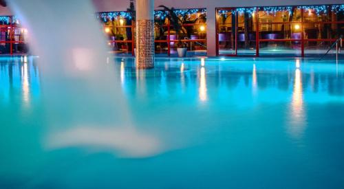 an empty swimming pool at night with a fountain at Wellness & Spa Hotel Kaskady in Sliač