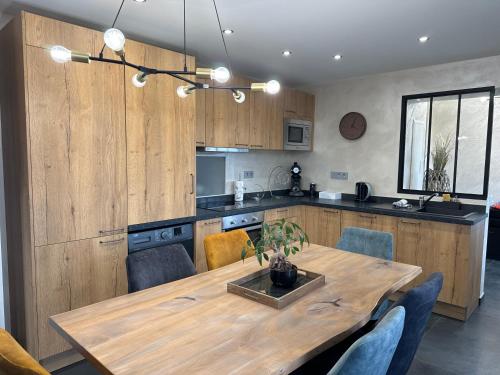 une cuisine avec une table en bois et des chaises bleues dans l'établissement la ruche Bel appartement avec terrasse, magnifique vue , 2 spa, à Gérardmer