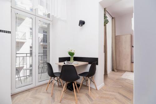 a dining room with a table and black chairs at Starowiślna Studio Kazimierz Cracow by Renters in Krakow