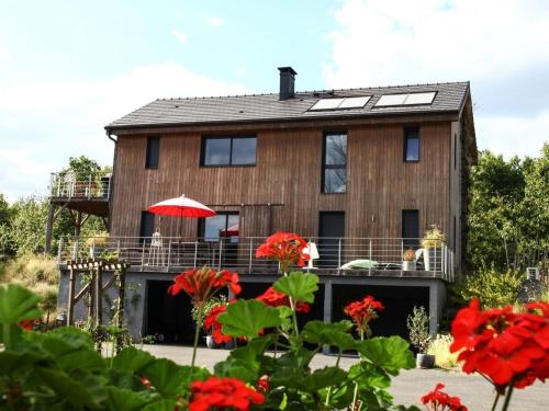 a wooden house with a balcony and red flowers at Le Domaine de l'Ô - Lofts Contemporain au Coeur du Perigord in Saint-Jean-dʼEyraud