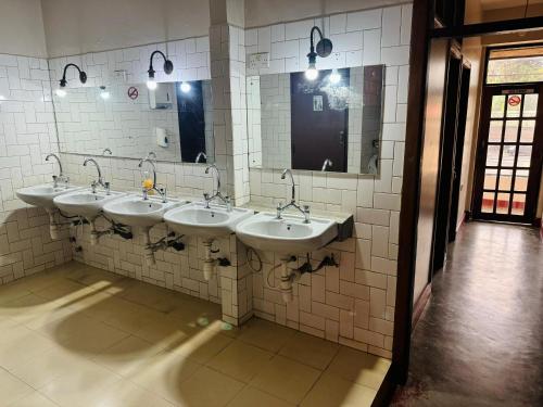 une rangée de lavabos dans une salle de bains commune dans l'établissement Arusha Backpackers Hotel, à Arusha