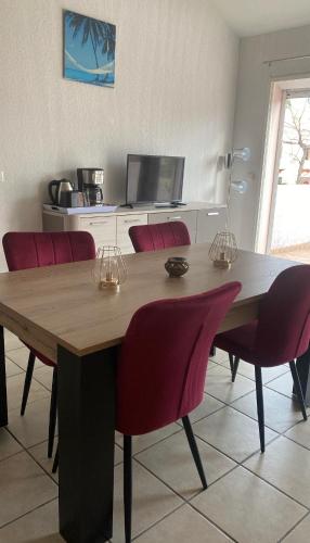 une table à manger avec des chaises rouges et une télévision dans l'établissement Appartement Argeles Plage, à Plage dʼArgelès