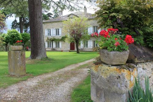 een huis met rode bloemen op een stenen muur bij Grande maison en pierre avec piscine, sauna et jacuzzi in Madaillan