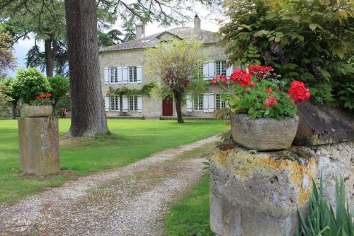 une maison avec des fleurs rouges au-dessus d'un mur en pierre dans l'établissement Grande maison en pierre de taille avec piscine, sauna et jacuzzi, à Madaillan