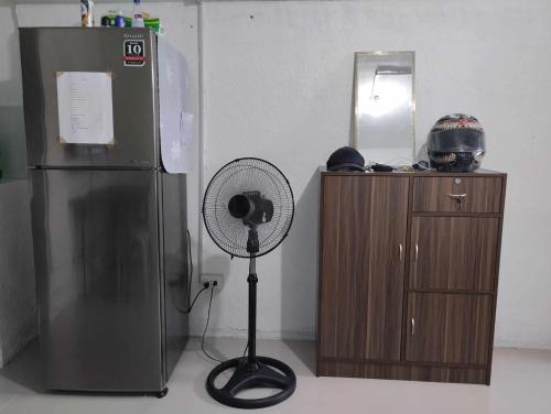 einen Ventilator neben einem Kühlschrank und einem Spiegel in der Unterkunft Vin's Place Rentals - Studio Unit in Tagum