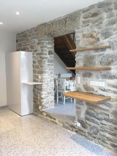 une pièce avec un mur en pierre avec un réfrigérateur dans l'établissement Le Récif, maison indépendante Corniche de la mer, à Concarneau