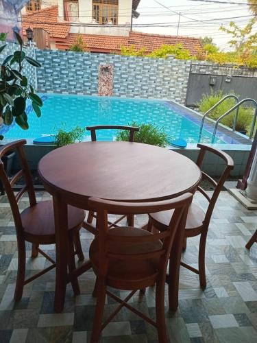 a wooden table and chairs next to a swimming pool at Andorra Tourist Resort Anuradhapura in Anuradhapura