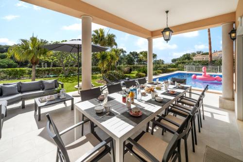 a patio with a table and chairs and a pool at Extraordinary Villa on an elevated position in Quinta do Lago in Quinta do Lago