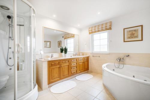 a bathroom with a tub and two sinks and a shower at Extraordinary Villa on an elevated position in Quinta do Lago in Quinta do Lago