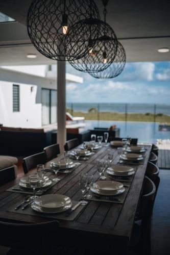 a long wooden table with plates and wine glasses at Stunning Beachfront Villa for a Perfect Getaway in Riambel