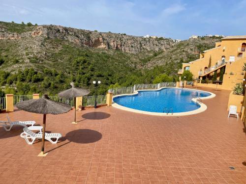 une piscine avec des chaises et des parasols et une montagne dans l'établissement Apartment Casa Lieja - Cumbre del Sol, à Cumbre del Sol