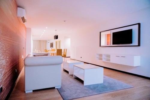 a living room with a couch and a tv on a wall at Beira Terrace Hotel in Beira