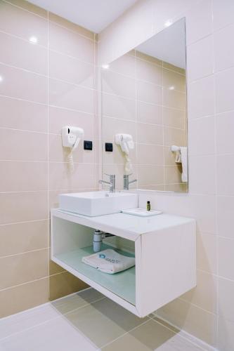 a white bathroom with a sink and a mirror at Beira Terrace Hotel in Beira
