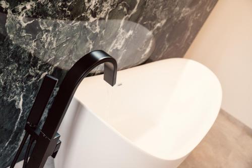 a white chair next to a wall with a faucet at NEW LUXUS Suite I TWO Kingbeds I Center in Augsburg