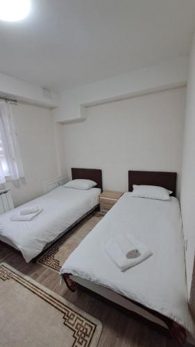 2 Betten in einem Zimmer mit weißer Bettwäsche in der Unterkunft Apartman Zirojević in Lukavica