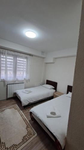 2 Betten in einem Zimmer mit weißen Wänden und Fenstern in der Unterkunft Apartman Zirojević in Lukavica