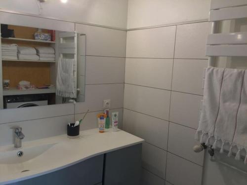 une salle de bain blanche avec un lavabo et un miroir dans l'établissement Appartement au Cœur de Ville : 6/8 personnes, à Briançon