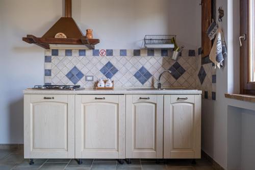 a kitchen with white cabinets and a sink at La Svolta - Aria in Manciano