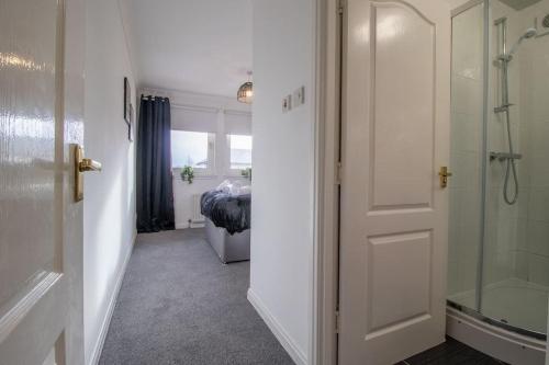 a bathroom with a shower and a bedroom with a bed at Park View-modern 2 bed apartment in Motherwell