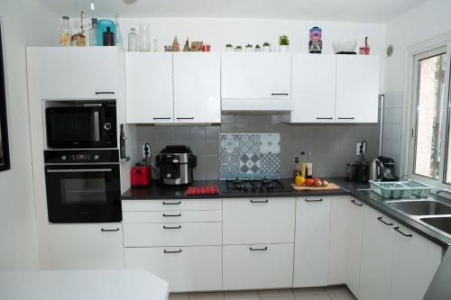 a white kitchen with white cabinets and black appliances at INZO in Montpellier