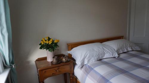 1 dormitorio con 1 cama con un jarrón de flores sobre una mesa en Dryden Gardens en Edimburgo
