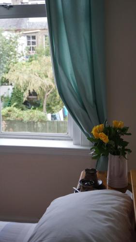una ventana con un jarrón con flores amarillas en una cama en Dryden Gardens en Edimburgo