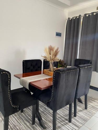 einen Esstisch mit schwarzen Stühlen und einem Tisch in der Unterkunft Queen City Homes in Lilongwe
