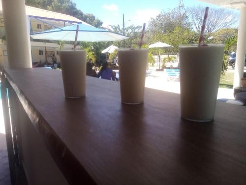 four drinks sitting on a bar with an umbrella at Malibu Dreams Village in Nueva Gorgona