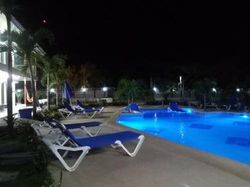 uma piscina à noite com espreguiçadeiras azuis em Malibu Dreams Village em Nueva Gorgona