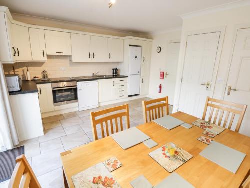 a kitchen with a wooden table and chairs in a kitchen at Sea Breeze Holiday Home in Enniscrone