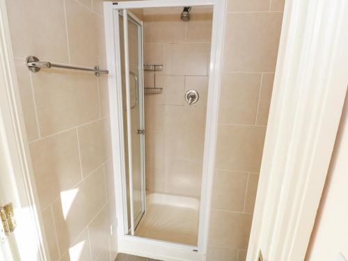 La salle de bains est pourvue d'une douche avec une porte en verre. dans l'établissement Sea Breeze Holiday Home, à Enniscrone