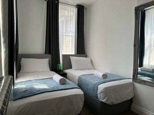 two beds in a room with a mirror at Holborn Apartments in London