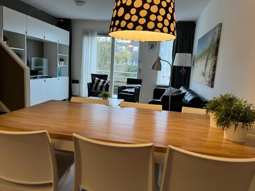 jadalnia i salon z drewnianym stołem i krzesłami w obiekcie Appartement Anker w mieście Hollum