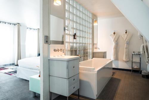 a white bathroom with a sink and a bath tub at Kube Hotel Paris in Paris