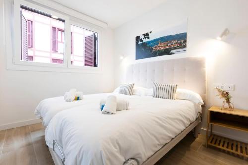 - une chambre avec un grand lit blanc et une fenêtre dans l'établissement Portuko. Basquenjoy, à Fontarrabie