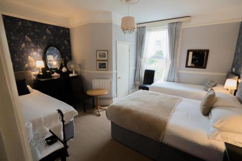 a bedroom with two beds and a desk and a mirror at Maison Dieu Guest House in Dover
