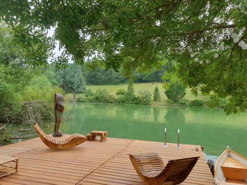 une terrasse en bois avec deux chaises et une statue sur un lac dans l'établissement tipi des apaches, à Moulayrès