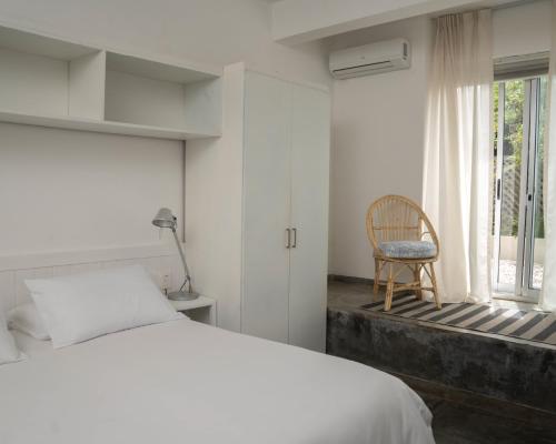 a bedroom with a bed and a chair and a window at La Posta Beach Hotel in Punta del Este