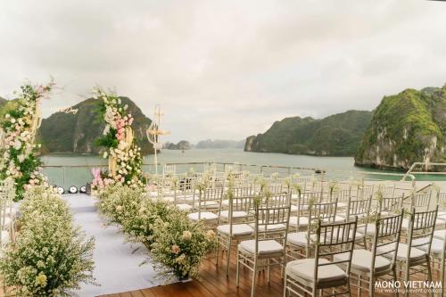 a wedding aisle with chairs and flowers on the water at Grand Pioneers Halong Bay Cruise 1 in Ha Long