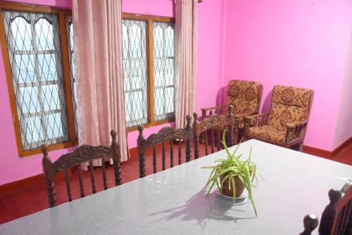 a table and chairs in a room with pink walls at Carmalin Holiday Bungalow in Nuwara Eliya