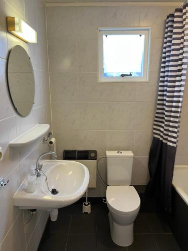 Un baño con inodoro, lavabo y ventana. en Appartement Anker, en Hollum