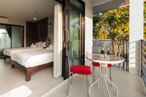 um quarto com uma cama e uma mesa com um banco vermelho em Tawang Home em Chiang Mai