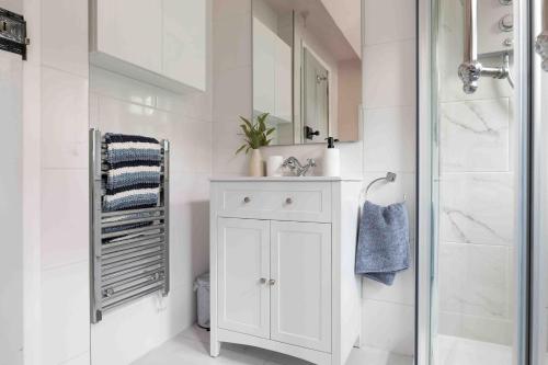 a white bathroom with a sink and a shower at Remarkable 1-Bed Cotswolds Cottage in Finstock in Chipping Norton