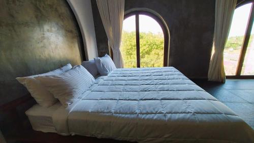 a bedroom with a large bed with two windows at Kave Hotels - Pondicherry in Puducherry