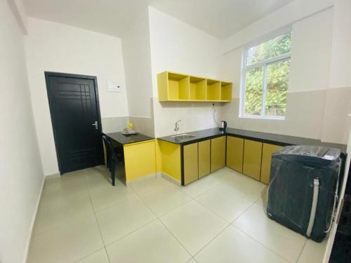 uma cozinha com armários amarelos e pretos e uma janela em Phoenix Residency, Near MVR Cancer Centre, Vellalassery, NIT, Calicut em Māvūr