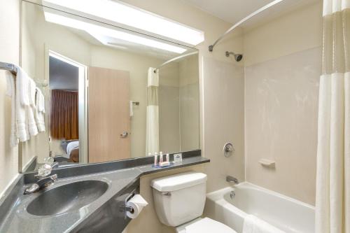 a bathroom with a sink and a toilet and a tub at Days Inn by Wyndham Florence Cincinnati Area in Florence