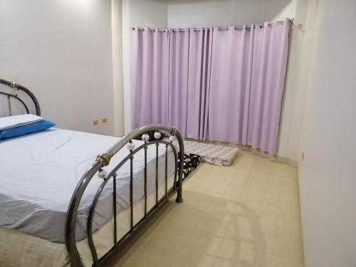 - une chambre avec un lit et des rideaux violets dans l'établissement JD Homestays CDO, à Cagayán de Oro