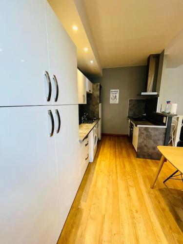 une cuisine avec des armoires blanches et un plancher en bois dans l'établissement LE BERCHON classé trois épis, à Nay